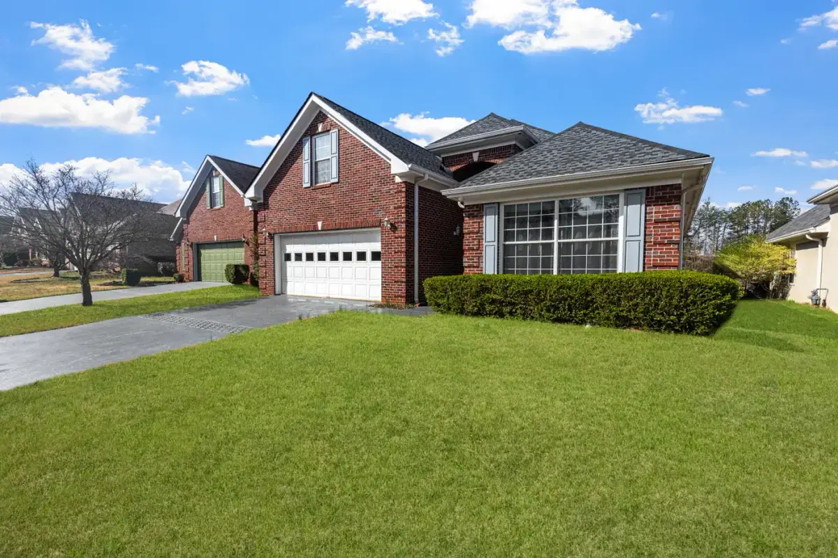 Red brick house with a clipped lawn on a clear day