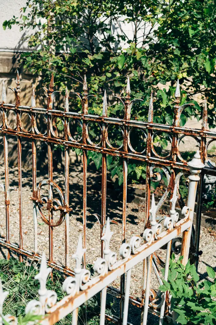 White painted iron fence with rust bleeding through the paint along the pickets