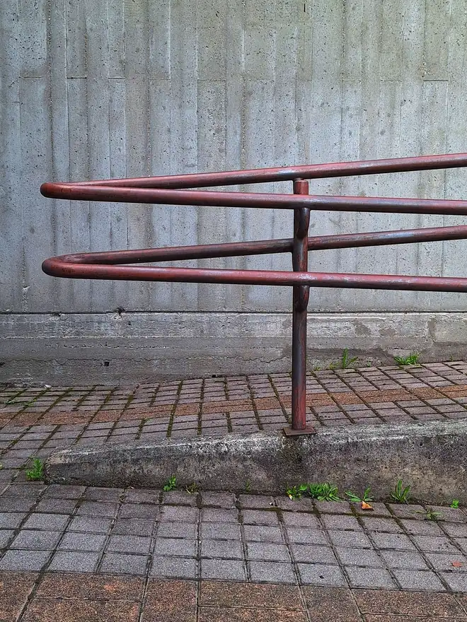 Weather streaks running down a concrete wall beside a painted steel handrail